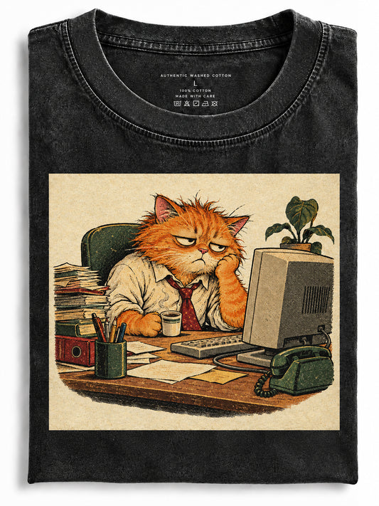 Folded black t-shirt featuring a grumpy orange cat sitting at an office desk with a computer