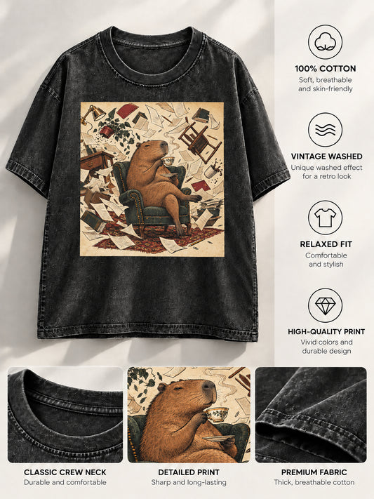 Black washed t-shirt displaying a relaxed capybara sipping tea with floating furniture illustration and fabric callouts