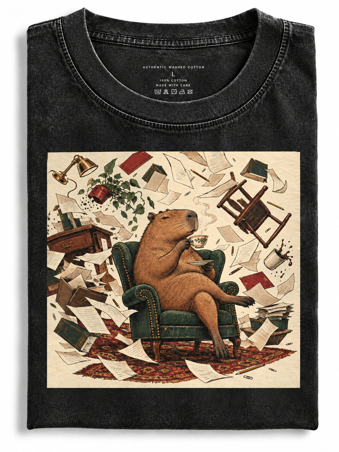 Folded black washed garment featuring a calm capybara drinking tea in an armchair amidst floating room chaos